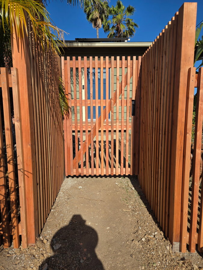 Black chain-link gate with lock box on a stone path in Summerland