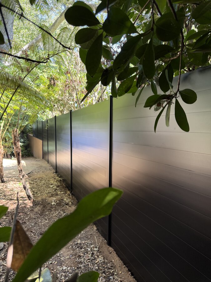 Black horizontal aluminum fence along a shaded garden path in Montecito