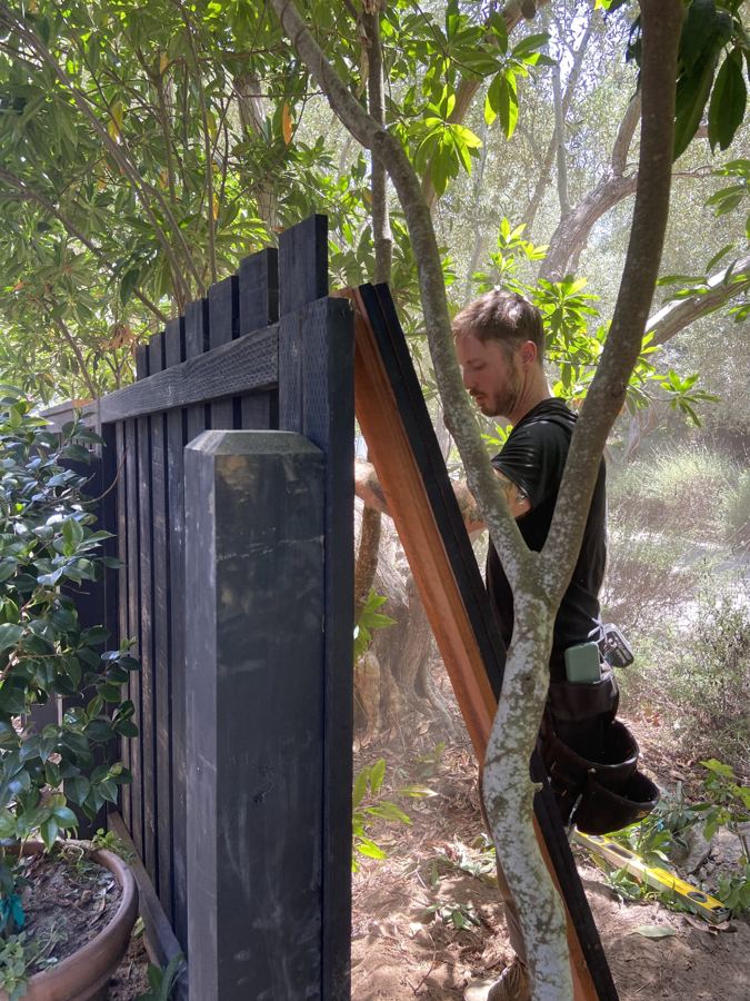 Black-stained custom board fence under construction