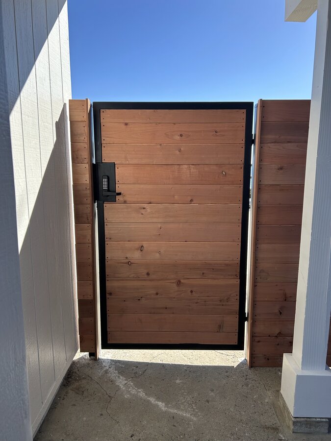 Cedar plank gate in a black steel frame at a Montecito side entrance