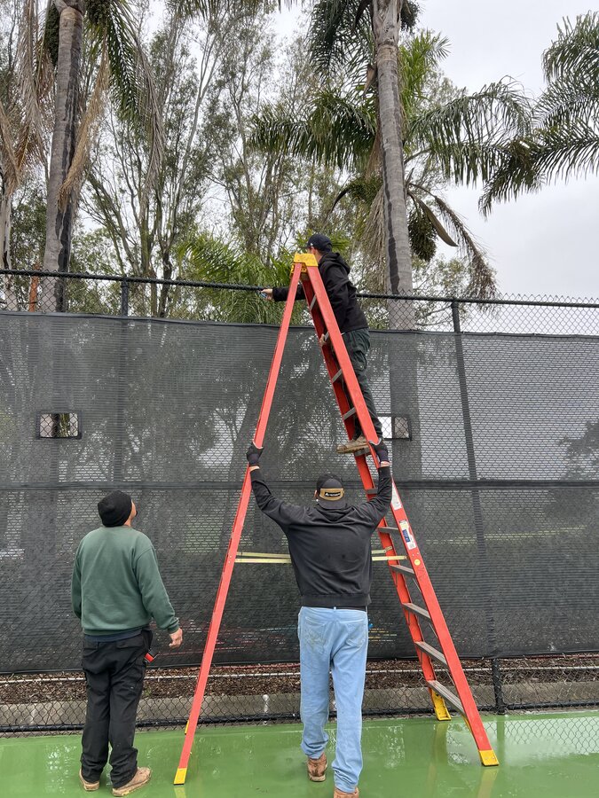 Lighthouse Fence crew installing black chain-link and privacy screening around a sports court in Santa Barbara