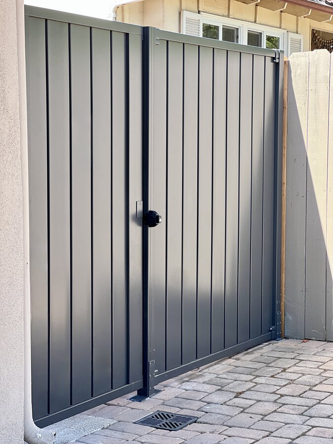 Dark barn-style double gate with X-bracing and an arched top in Montecito