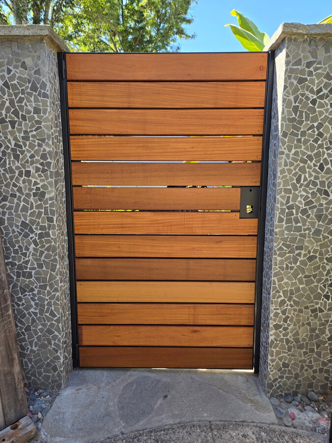 Golden Balau horizontal gate with steel frame and electronic strike, set in a stone-mosaic wall in Montecito