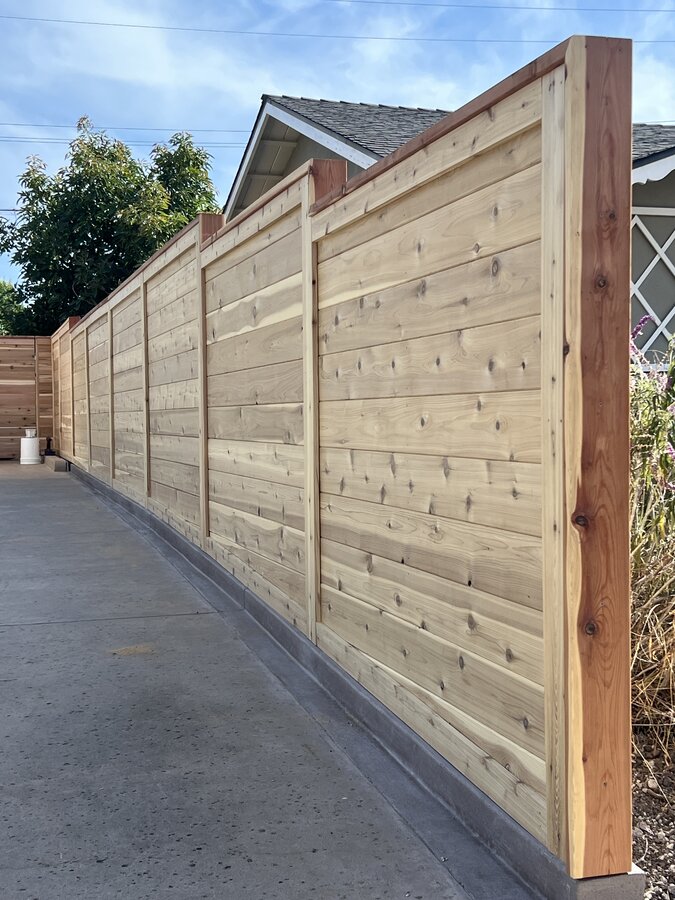 Horizontal cedar fence with a redwood cap rail along a driveway in Goleta