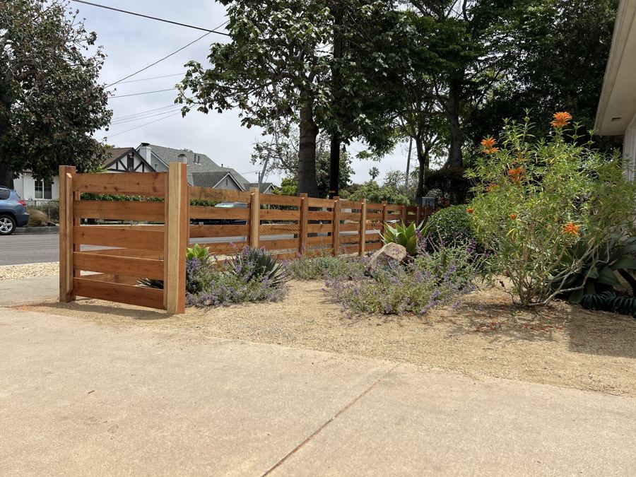 Horizontal slat wood fence at a driveway entrance