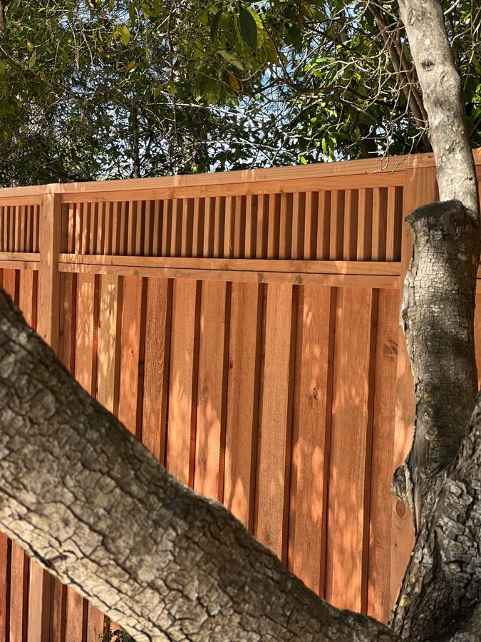 Stained board fence with detailed top treatment
