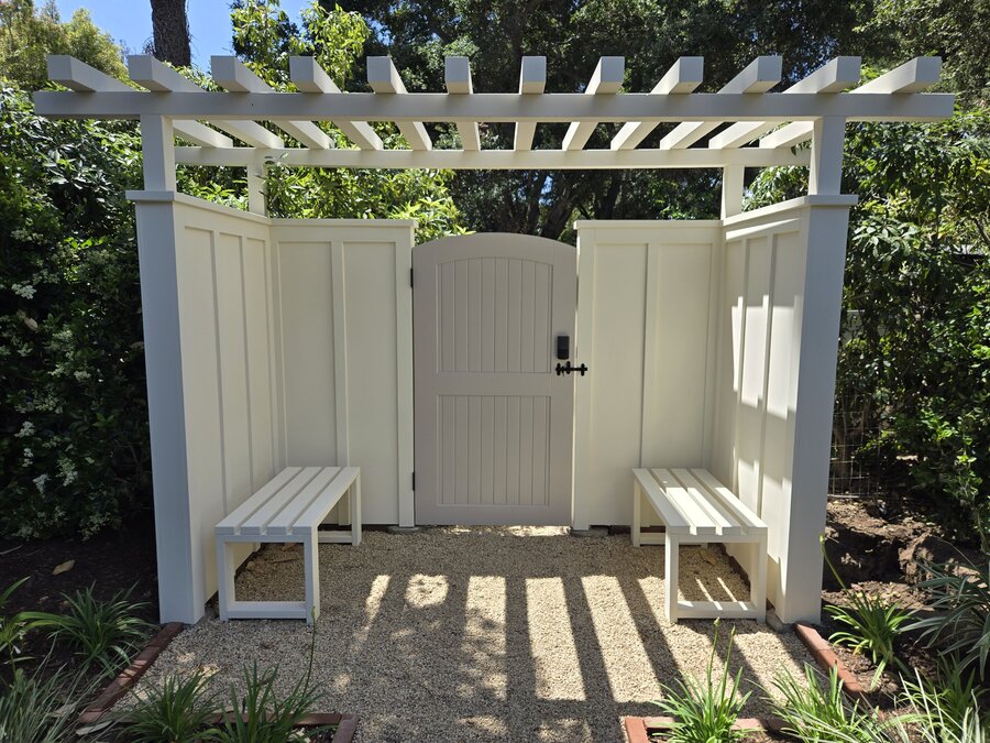 White pergola-topped gate structure with built-in benches in Montecito